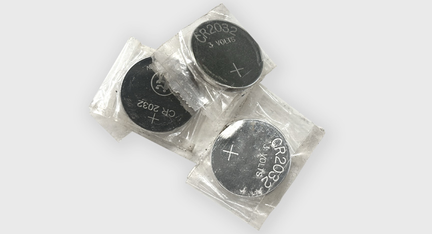 Various sized button batteries in separate plastic bags piled up together.