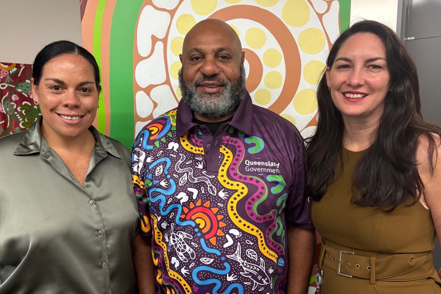 CHQ Executive Director Aboriginal and Torres Strait Islander Engagement Angela Young (left), Cultural Capability Lead Daniel Tapau and CHQ Executive Director People and Governance Naomi Hebson standing together in front of an Aboriginal artwork.