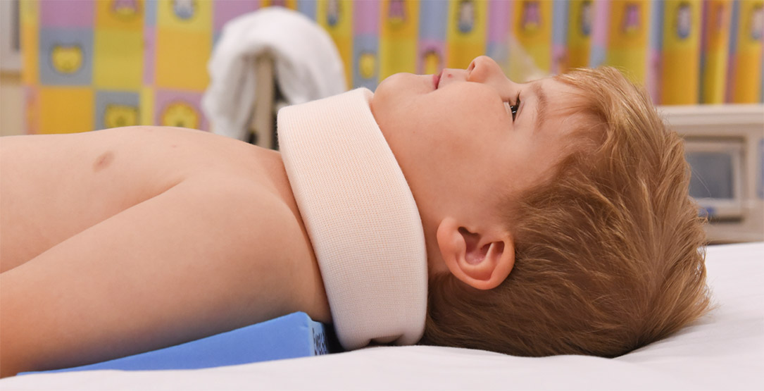 Child lying on a hospital bed with a neck collar to protect from cervical spine injury