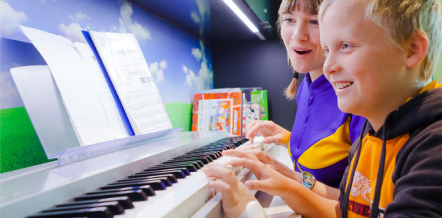 Child playing piano with starlight express room volunteer